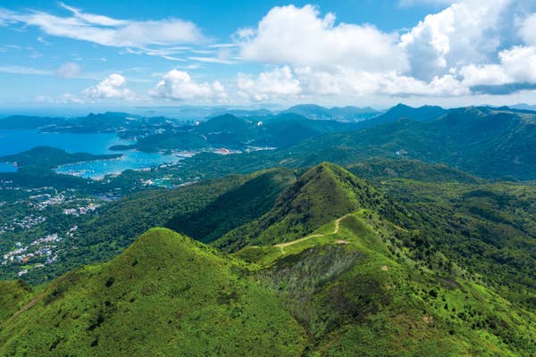 Scenic coastal view with towering cliffs under the sunset, calm ocean waters, and distant islands; a travel destination highlight
